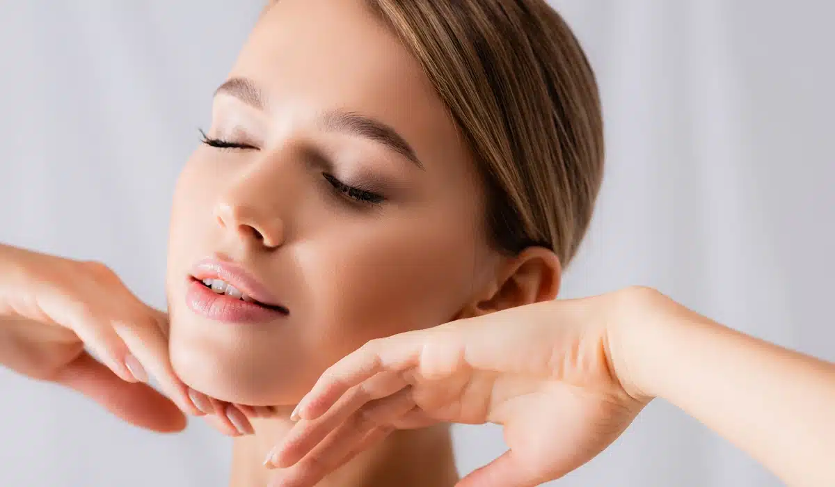 A close-up of a person touching their jawline, highlighting the smooth, rejuvenated skin and reduced appearance of wrinkles achieved with Jeuveau
